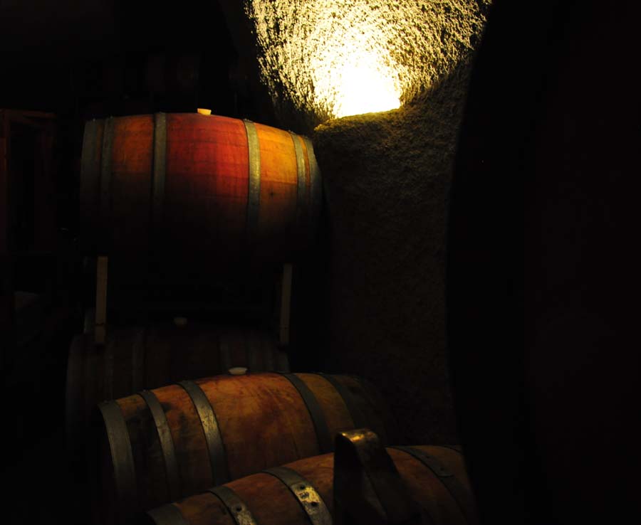 Oak barrels stacked inside the winery's cave, lit from the far end